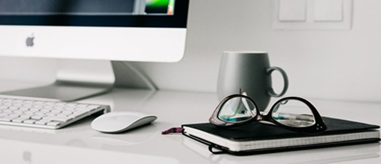 picture of a imac in the background with note pad in the foreground and glasses sitting on top of it on top of a computer design for website design