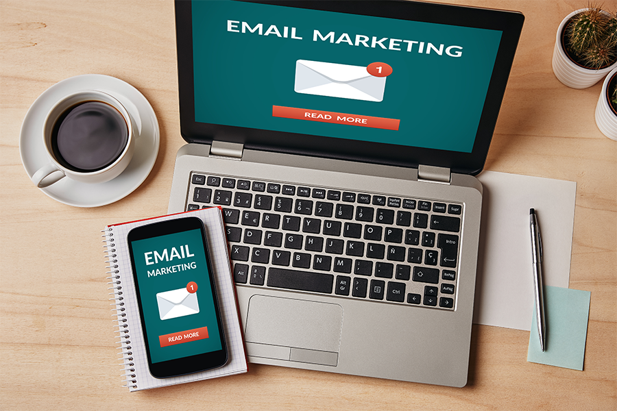 phone and a computer on a desk with the words email marketing on the phone screen and laptop screen